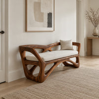 Bench with a sculpted open wooden frame, low arms and a pale cushion in a Scandinavian entryway with white walls