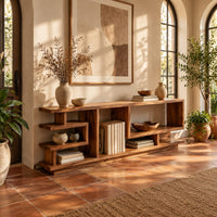 Open shelf console table with stepped square cubbies on a slim plinth in a bright entryway with arched windows and plants