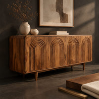 Corner detail of sideboard with four arch carved doors and slim tapered legs beside wood, brass and linen samples