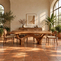 Live edge dining table with arching branch legs under a slab top in a bright dining room with arched windows and plants