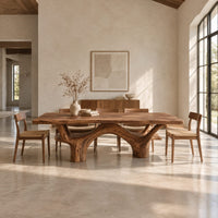 Live edge dining table with arching branch legs under a slab top in a bright open plan dining room