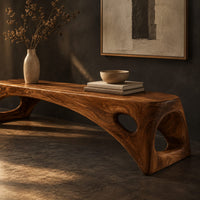 Corner detail of arched bench with oval cutouts in the end legs beside wood, brass and linen samples