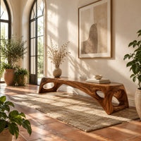 Arched bench with oval cutouts in the end legs in a bright entryway with arched windows and plants