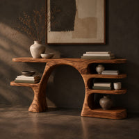 Corner detail of arched console table with a branch shaped leg and stacked oval shelves beside wood, brass and linen samples