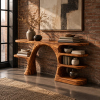 Arched console table with a branch shaped leg and stacked oval shelves in an industrial loft entryway with exposed brick