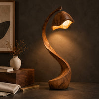 Corner detail of floor lamp with a long arching wooden stem and a carved hood shade beside wood, brass and linen samples