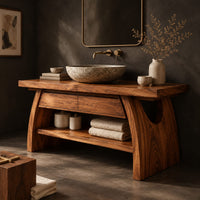 Corner detail of wood vanity with a thick plank top and arched legs over an open shelf beside wood, brass and linen samples