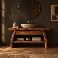 Wood vanity with a thick plank top and arched legs over an open shelf in a dark bathroom at golden hour