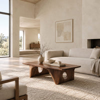 Thick slab coffee table on carved arch legs with circular cutouts in a bright open plan living room