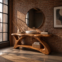 Freestanding vanity with a long slab top on an asymmetric sculpted base in an industrial loft bathroom with exposed brick