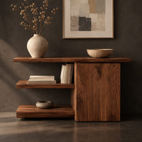 Corner detail of asymmetric console table with two open shelves beside a closed wood block beside wood, brass and linen samples