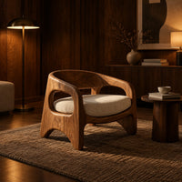 Low barrel back chair with oval side openings and arched legs in an evening living room with walnut wall paneling