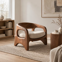 Low barrel back chair with oval side openings and arched legs in a Scandinavian living room with white walls