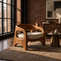 Low barrel back chair with oval side openings and arched legs in an industrial loft living room with exposed brick