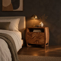 Barrel sided nightstand with an open top cubby and a swirled grain front in a dark bedroom at golden hour