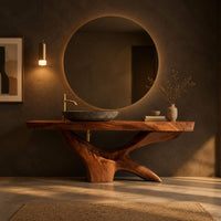 Freestanding bathroom vanity with a thick slab top on a carved forked base in a dark bathroom at golden hour