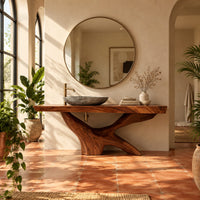 Freestanding bathroom vanity with a thick slab top on a carved forked base in a bright bathroom with arched windows and plants