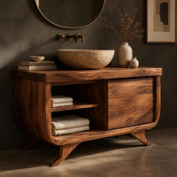 Corner detail of bathroom vanity with an open cubby and one door on flared feet beside wood, brass and linen samples