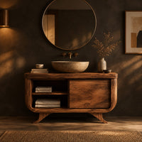 Bathroom vanity with an open cubby and one door on flared feet in a dark bathroom at golden hour
