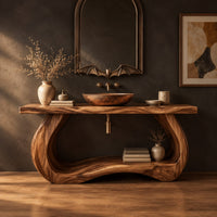 Bathroom vanity with a thick slab top on a sculpted loop base in a dark studio against a charcoal plaster wall