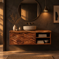 Bathroom vanity with wave carved doors and an open shelf bay in a dark bathroom at golden hour