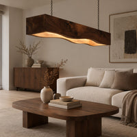 Long beam pendant light with a wavy lower edge and a warm glow in a Scandinavian living room with white walls