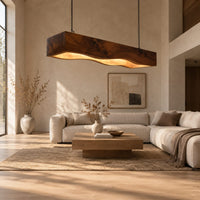 Long beam pendant light with a wavy lower edge and a warm glow in a bright open plan living room