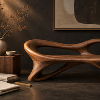 Corner detail of bench with a flowing frame and large oval openings beside wood, brass and linen samples