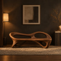 Bench with a flowing frame and large oval openings in a dark entryway at golden hour