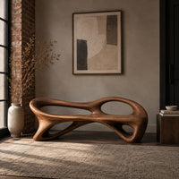 Bench with a flowing frame and large oval openings in an industrial loft entryway with exposed brick
