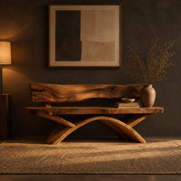 Bench with a natural edge slab back and angled arched legs in a dark entryway at golden hour
