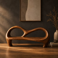 Bench with an open looping backrest and sculpted legs in a dark studio against a charcoal plaster wall