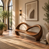 Bench with an open looping backrest and sculpted legs in a bright entryway with arched windows and plants