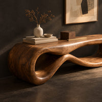 Corner detail of low wood bench shaped as a figure eight loop with a smooth top beside wood, brass and linen samples