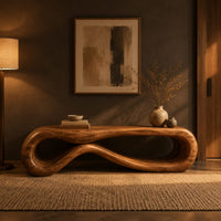 Low wood bench shaped as a figure eight loop with a smooth top in a dark entryway at golden hour