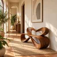 Bench with a heart shaped open back and a folded ribbon seat in a bright entryway with arched windows and plants
