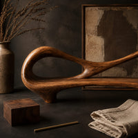 Corner detail of bench with an open loop backrest and sculpted feet beside wood, brass and linen samples