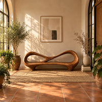 Bench with an open loop backrest and sculpted feet in a bright entryway with arched windows and plants