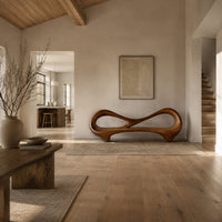 Bench with an open loop backrest and sculpted feet in a bright open plan entryway