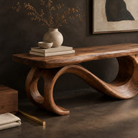 Corner detail of bench with a plank seat on an s shaped scroll base beside wood, brass and linen samples