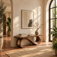 Bench with a plank seat on an s shaped scroll base in a bright entryway with arched windows and plants