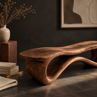Corner detail of low wood bench with a wavy slab top on an open ribbon loop base beside wood, brass and linen samples