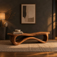 Low wood bench with a wavy slab top on an open ribbon loop base in a dark entryway at golden hour
