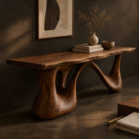 Corner detail of long low slab bench with a wavy edge on a sculpted base beside wood, brass and linen samples