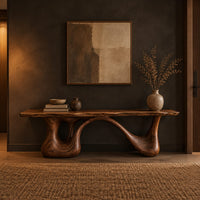 Long low slab bench with a wavy edge on a sculpted base in a dark entryway at golden hour