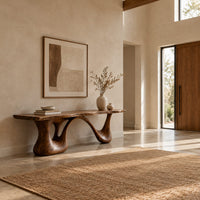 Long low slab bench with a wavy edge on a sculpted base in a bright open plan entryway