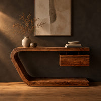 Console table with a bent slab frame and a floating box under the top in a dark studio against a charcoal plaster wall