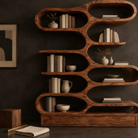 Corner detail of bookshelf with staggered pill shaped open cubbies above a low base beside wood, brass and linen samples