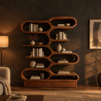 Bookshelf with staggered pill shaped open cubbies above a low base in a dark living room at golden hour
