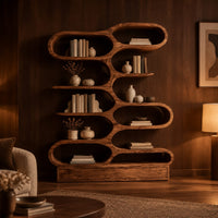 Bookshelf with staggered pill shaped open cubbies above a low base in an evening living room with walnut wall paneling